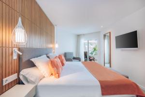 a bedroom with a large white bed and a tv at Iberostar Waves Playa de Muro in Playa de Muro
