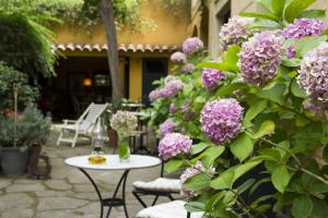 un patio con flores púrpuras, mesa y sillas en Caldescans Bed&Breakfast, en Caldes d'Estrac