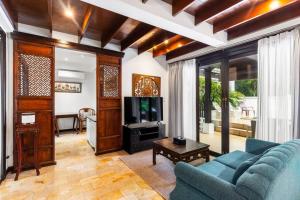 un salon avec un canapé bleu et une télévision dans l'établissement Sclass Villa & Swimming pool , 10 min from airport, à Chiang Mai