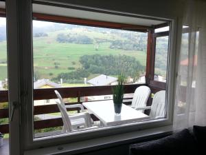 Cette chambre dispose d'une fenêtre avec une table et des chaises blanches. dans l'établissement Tgesa Tgampi T20, à Savognin