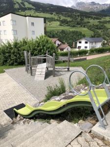 a playground with a green slide and a bench at Tgesa Tgampi T20 in Savognin