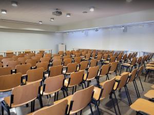 Hostatgeria de Poblet في بوليت: غرفة محاضرات فارغة مع مكاتب وكراسي