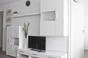 a white living room with a tv on a white cabinet at Tgesa Tgampi T20 in Savognin