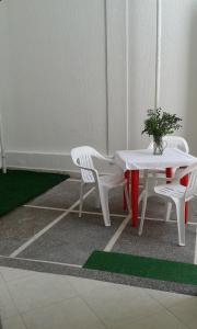 two white chairs and a table with a potted plant on it at Hotel Comercial Neiva in Neiva