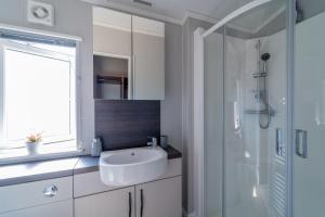 een witte badkamer met een wastafel en een douche bij Number Four - Piran View in Padstow +15 foto's