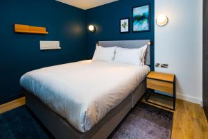 a large bed in a room with blue walls at Staybridge Suites - Cardiff, an IHG Hotel in Cardiff