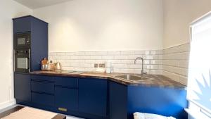 a kitchen with blue cabinets and a sink at urchin Loft in Ardmore +33 photos