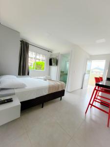 a bedroom with a large bed and a red chair at Hospeda Mariscal Flat in Bombinhas
