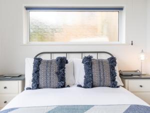 a bed with blue and white pillows and a window at Pass the Keys One bed flat with stunning views and free parking in Bath