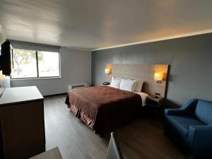 Pokój hotelowy z łóżkiem i niebieskim krzesłem w obiekcie Super 8 by Wyndham Fort Worth Entertainment District w mieście Fort Worth