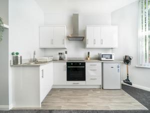 a white kitchen with white cabinets and appliances at Pass the Keys Pristine 1BR Apt Queens Uni Walk Everywhere in Belfast