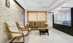 uma sala de estar com um sofá, cadeiras e uma mesa em Treebo Trend Elite Premium Homes em Bangalore