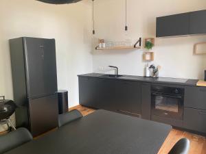 una cocina con armarios negros, fregadero y mesa en Huis Louis, en Kortessem