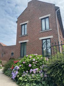 a brick house with flowers in front of it at Huis Louis in Kortessem +7 photos