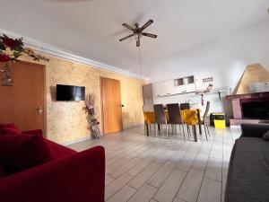 un soggiorno con ventilatore a soffitto, tavolo e sedie di Casa Planet a Montalbano Ionico