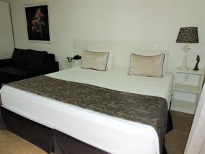 ein großes weißes Bett in einem Zimmer mit Stuhl in der Unterkunft Hotel Água Viva - By UP Hotel in Cachoeira Paulista