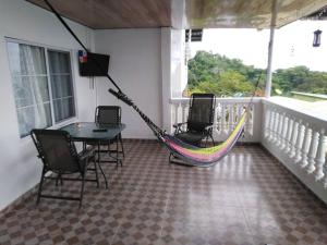 um alpendre com uma rede de descanso, uma mesa e cadeiras em La casa de Wili Taboga 62,61,00,07 em Taboga
