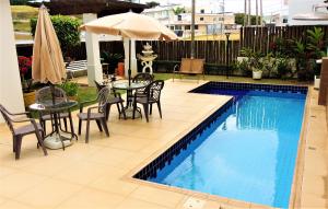 a swimming pool with a table and chairs and an umbrella at Hotel Água Viva - By UP Hotel in Cachoeira Paulista