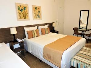 a hotel room with two beds and a mirror at Hotel Água Viva - By UP Hotel in Cachoeira Paulista