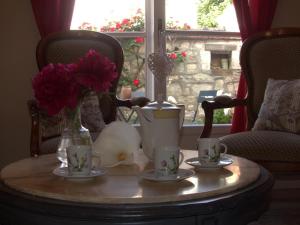 Una mesa con dos tazas y un jarrón con flores. en Gîte Moderne 10 Pers. en Touraine avec Jardin, WiFi, Près de la Vienne et Vignobles de Chinon - FR-1-381-395, en Cravant-les-Coteaux