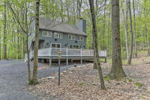 a large gray house with a porch in the woods at Updated Stroudsburg Home with Spacious Deck! in Stroudsburg