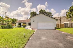 a white house with a garage in a yard at Lovely Lauderhill Retreat Less Than 12 Mi to Beach! in Lauderhill