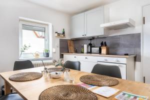 uma cozinha com uma mesa de madeira com cadeiras e uma sala de jantar em Stay Awesome - Modernes Apartment am Botanischen Garten em Kassel
