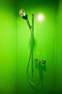 La salle de bains est pourvue d'une douche verte et d'un mur vert. dans l'établissement Hotel Alte Gärtnerei, à Härkingen