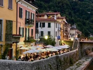 una calle con mesas y sombrillas en un pueblo en Locanda Posta, en Argegno