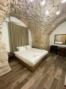 sypialnia z dużym łóżkiem w kamiennej ścianie w obiekcie Petrakis Inn w Jerozolimie