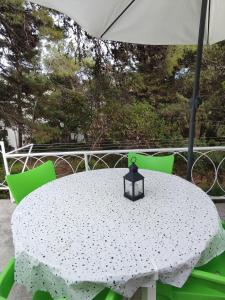 una mesa blanca con sillas verdes y sombrilla en Holiday Home Paradizo, en Veli Lošinj