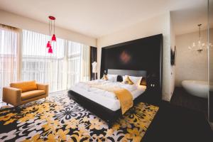 a bedroom with a bed and a tub and a chair at Kameha Grand Bonn in Bonn