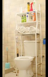 a bathroom with a toilet and a shelf with towels at PEARL LULU MODERN BNB Homestay in Dar es Salaam