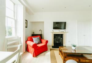 ein Wohnzimmer mit einem roten Stuhl und einem Tisch in der Unterkunft Luxury 1 Bed Flat, Spectacular Views Of Bath in Bath