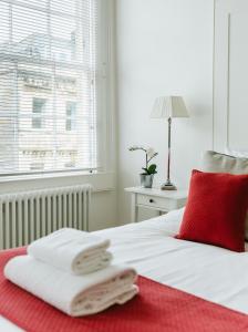 una camera da letto con cuscino rosso e asciugamani su un letto di Luxury 1 Bed Flat, Spectacular Views Of Bath a Bath