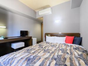 1 dormitorio con cama y escritorio en Tabist IWATA Station Hotel en Iwata