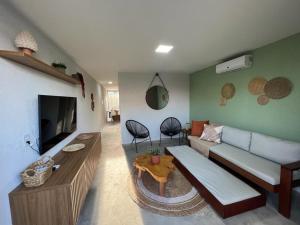 a living room with a couch and a tv at Casa Coralli Milagres ER Hospedagens in São Miguel dos Milagres