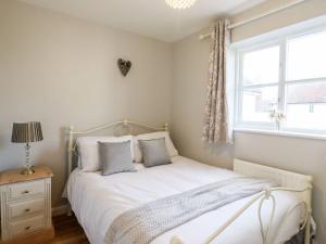 a bedroom with a bed with white sheets and a window at Cherry Blossom Place in Tiptree
