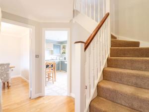 a staircase in a home with white walls and wood floors at Cherry Blossom Place in Tiptree