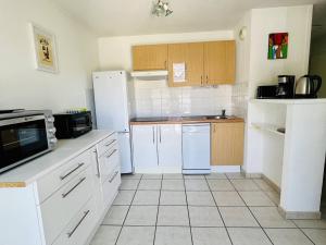 a kitchen with white appliances and wooden cabinets at Appartement T2 avec Piscine, Proche Thermes, Parking Souterrain et Terrasse - Cambo-les-Bains - FR-1-495-72 in Cambo-les-Bains +11 photos