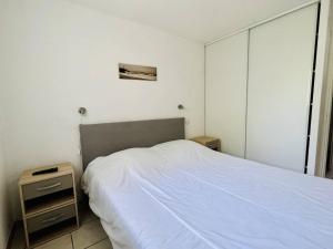 1 dormitorio con cama blanca y mesita de noche en Appartement Cambo-les-Bains, 2 pièces, 2 personnes - FR-1-495-72, en Cambo-les-Bains