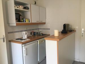 Elle comprend une petite cuisine avec des placards blancs et un évier. dans l'établissement Appartement Cabourg, 2 pièces, 2 personnes - FR-1-487-313, à Cabourg