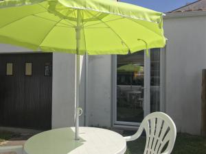 - une table avec un parasol vert et une chaise blanche dans l'établissement Maison La Tranche-sur-Mer, 3 pièces, 5 personnes - FR-1-22-321, à La Tranche-sur-Mer