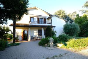 ein weißes Haus mit einem Balkon und einer Auffahrt in der Unterkunft Sotto la luna Casa in campagna in Castel Bolognese