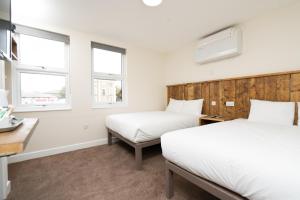 two beds in a room with two windows at Hotel DC, Stratford in London