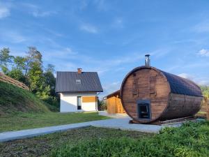 a large wooden barrel house next to a house at Sielska Osada - domki całoroczne in Rudenka
