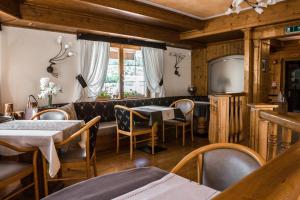 a restaurant with tables and chairs and a television at Hotel Al Parco in Moena