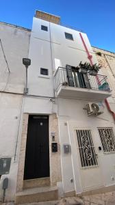 a white building with a black door and a balcony at 800s Home Luxury Rooms in Ostuni