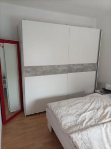 een slaapkamer met een wit bed en een spiegel bij Apartman Ana 1 in Valpovo