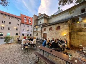 un grupo de personas sentadas en mesas frente a un edificio en Residenz am Roten Tor en Augsburg